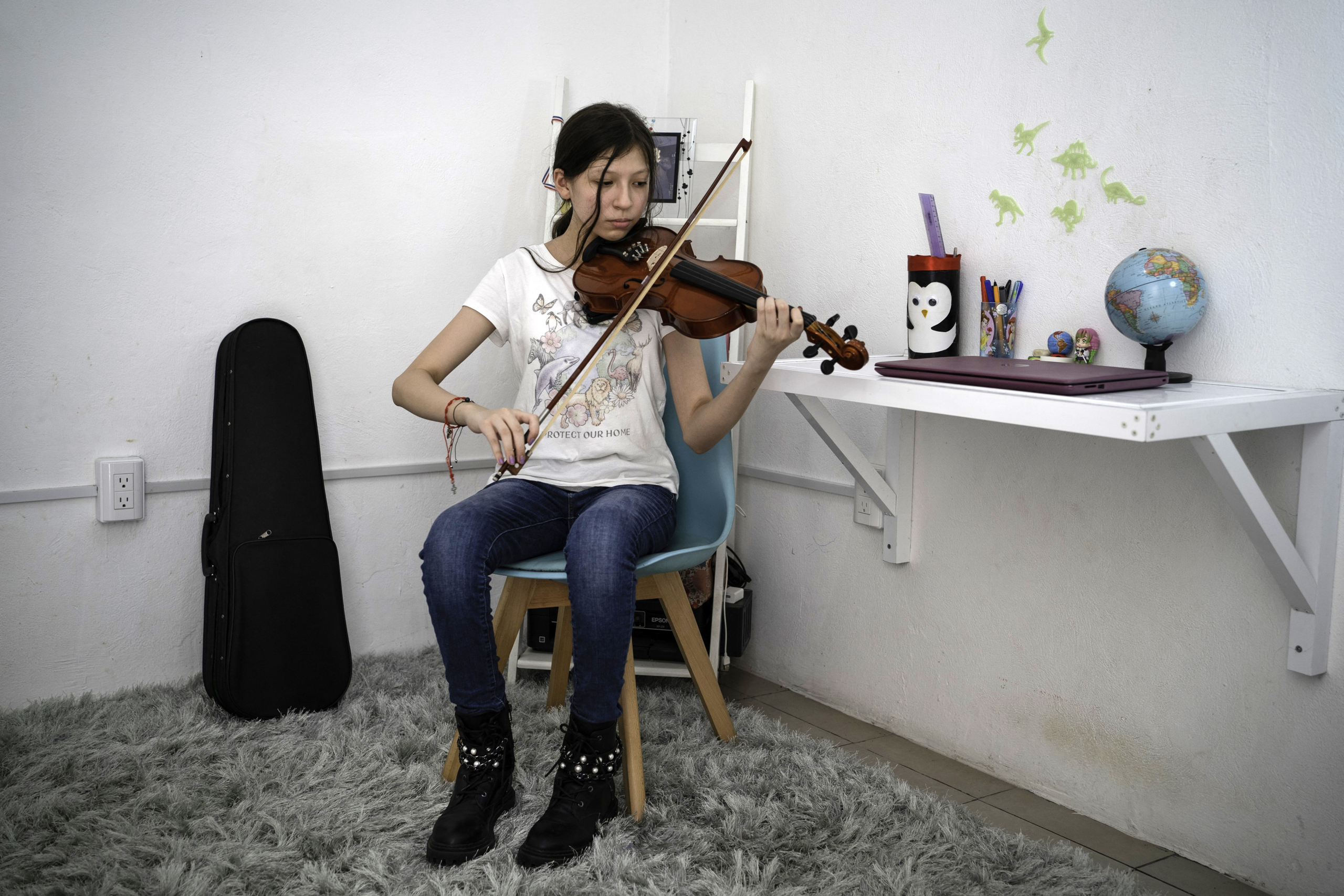 Karla Paola Esquivel, 12, plays the violin at her house in Veracruz, Mexico on August 23, 2021. - Karla's father Cesar Augusto Fernandez died of Covid-19 after being infected working in an oil tanker. With just days to go before school restarts in Mexico, Andrea Montero, mother of three children shaken by the sudden death of their father from covid-19, has made up her mind: her children will not attend school in person. (Photo by VICTORIA RAZO / AFP)