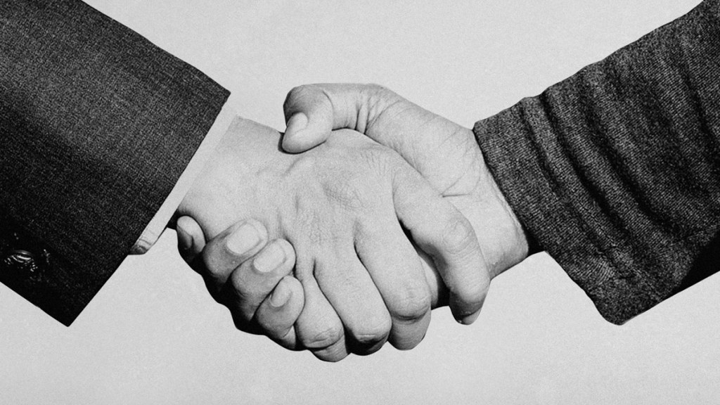 Dos manos entrelazadas en un apretón de manos, simbolizando un acuerdo o una colaboración.