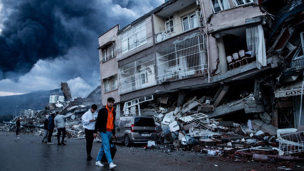 Personas caminando cerca de edificios dañados por terremotos en Turquía
