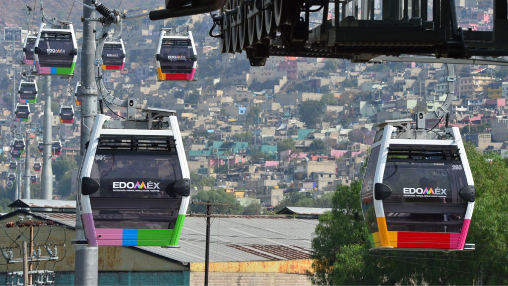 Cabinas de teleférico en Edomex, con construcción moderna y vistas de la ciudad de fondo.