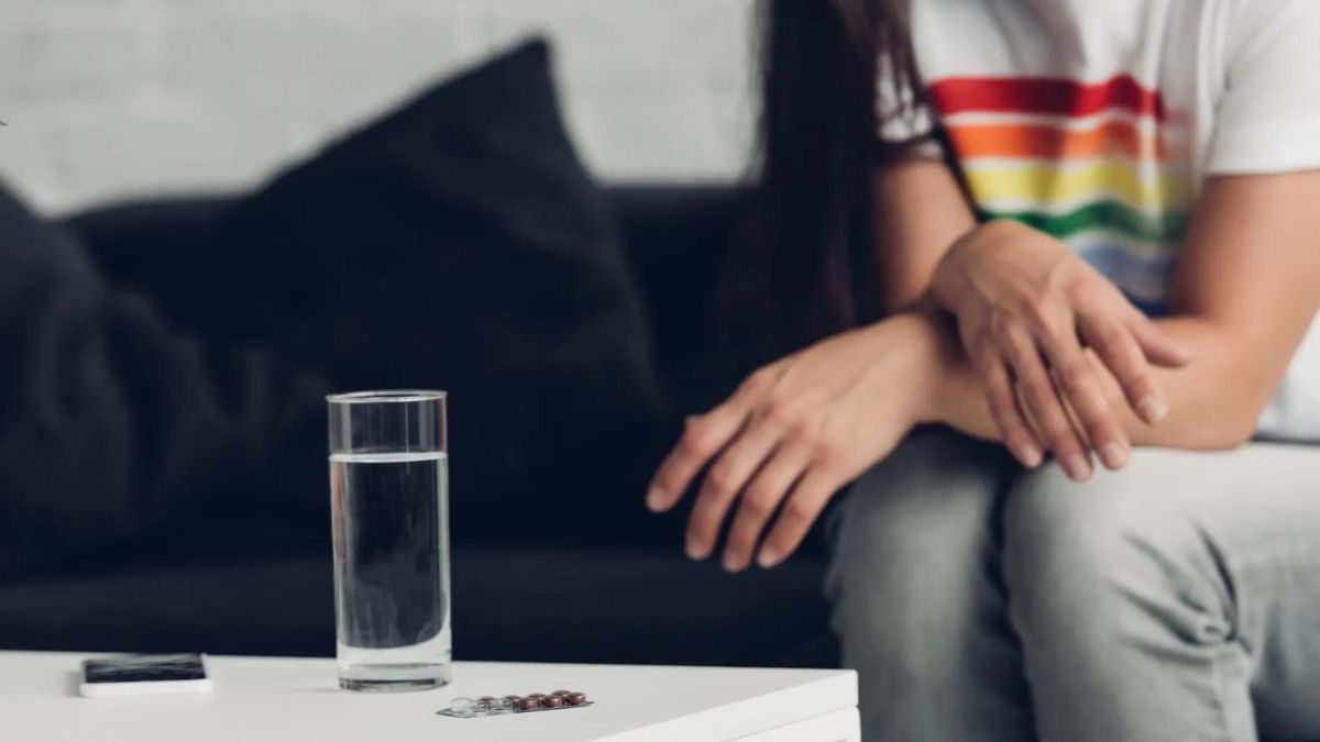 Persona frente a un vaso de agua con pastillas