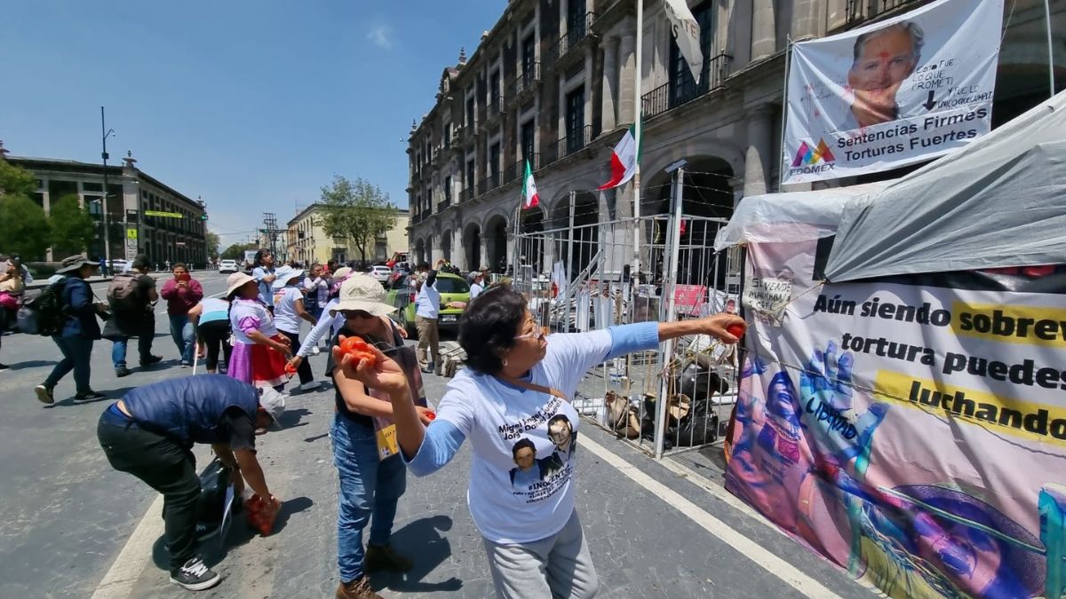 Mujeres lanzando jitomates a lona de Del Mazo