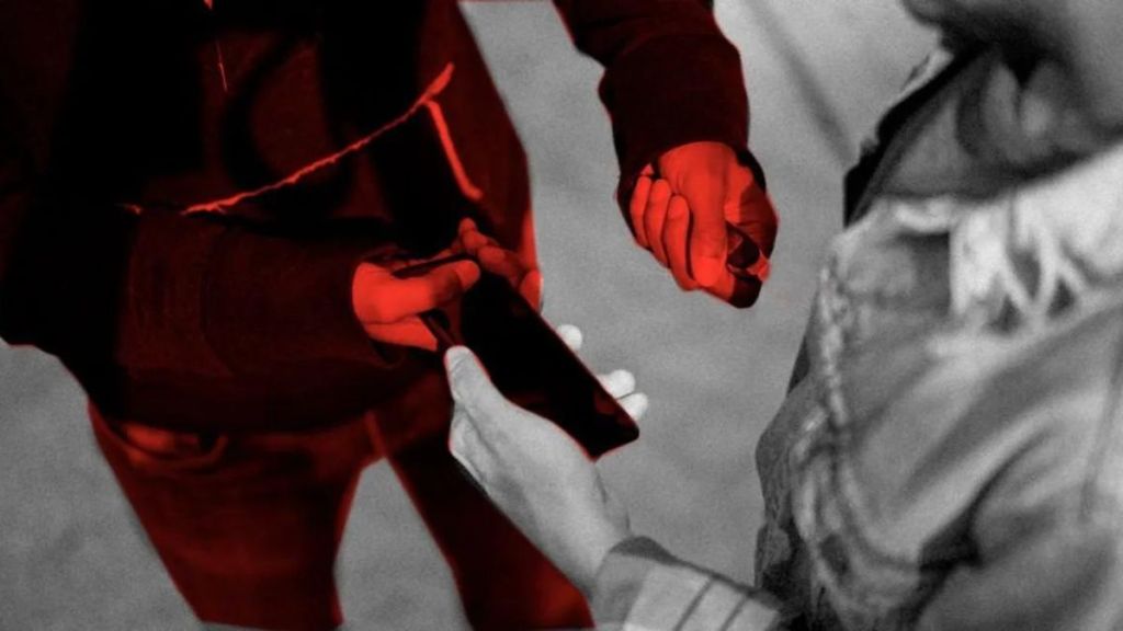 Dos manos intercambiando un teléfono móvil, con un efecto visual en rojo en la imagen.