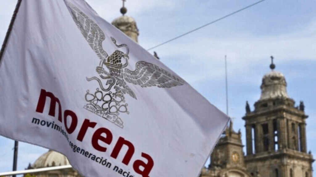 Una bandera del partido Morena con el logo del águila y el texto 'movimiento regeneración nacional' en un fondo de edificios históricos.