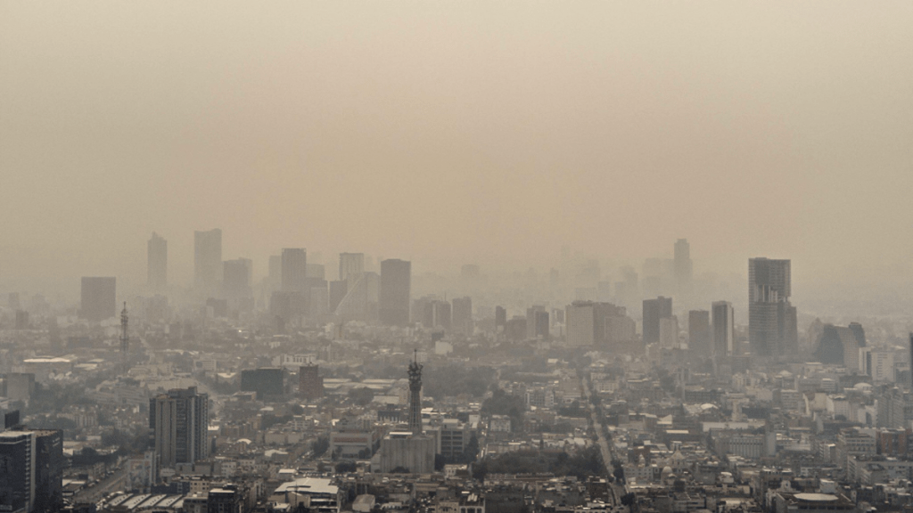 Vista de la Ciudad de México afectada por contaminación atmosférica, con edificios visibles en un ambiente brumoso y polvoriento.