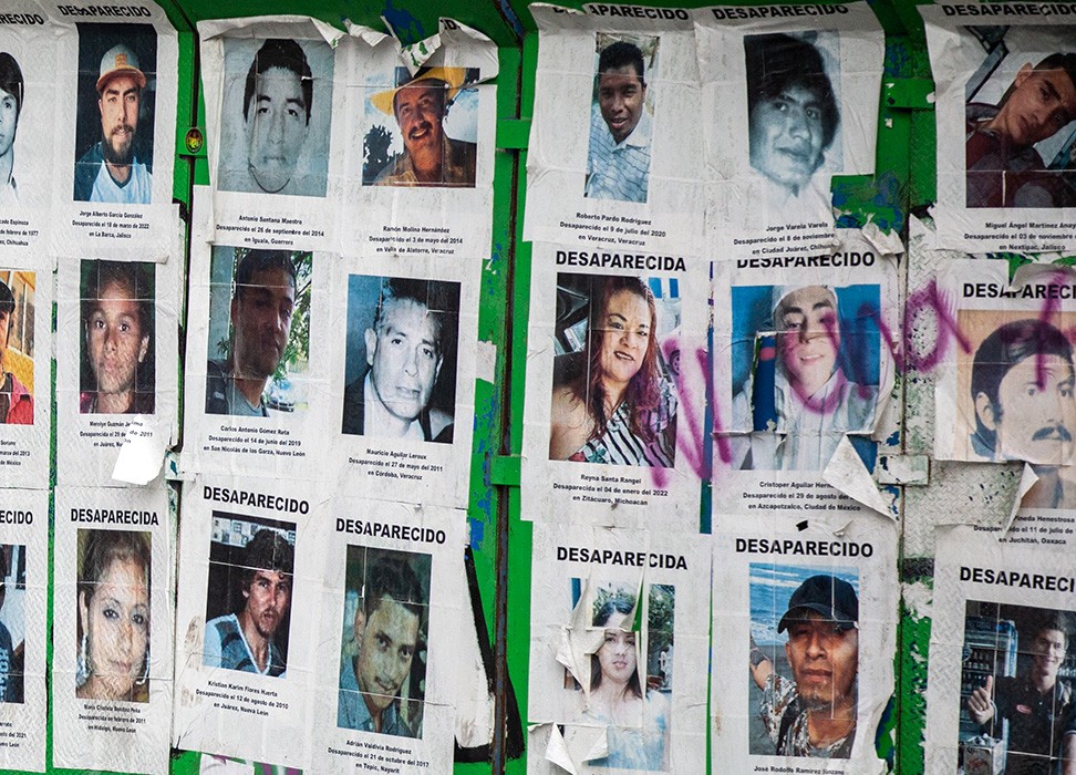Pósteres de personas desaparecidas en una pared, mostrando fotos y detalles de contacto para búsqueda.