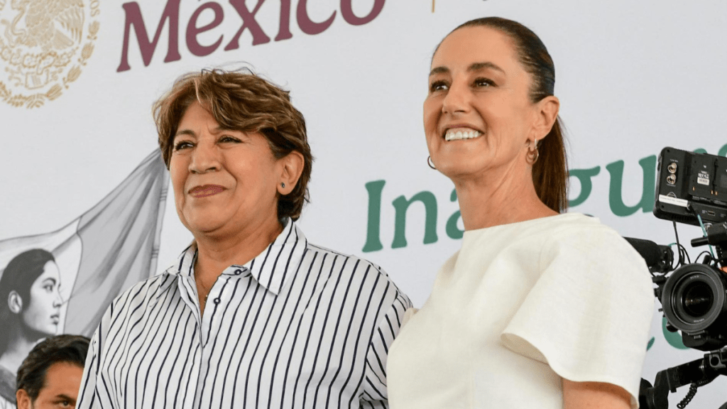 La gobernadora del Estado de México, Delfina Gómez Álvarez, y la presidenta Claudia Sheinbaum, sonriendo durante un evento en Nezahualcóyotl, con un fondo que muestra la bandera de México y un mensaje de inauguración.