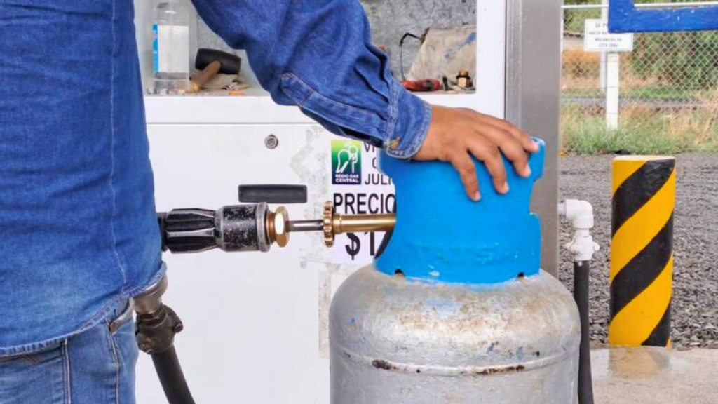 Una persona manipulando un cilindro de gas LP en una estación de servicio.