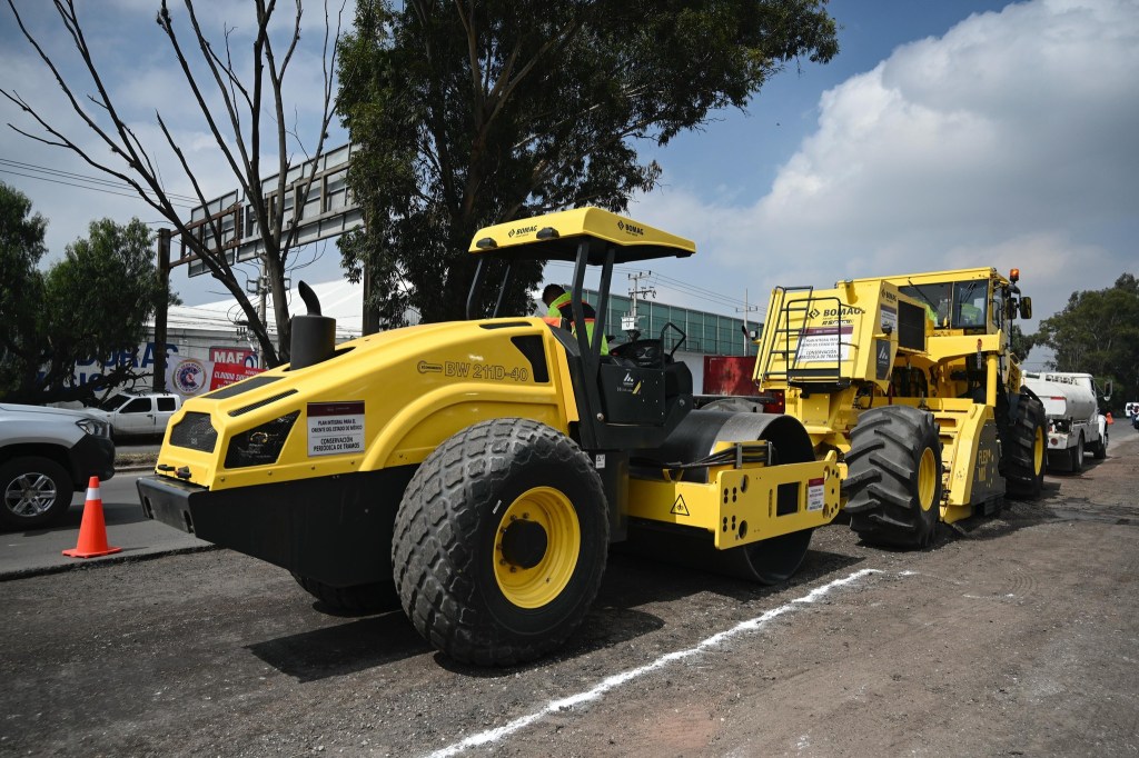Maquinaria amarilla de construcción para repavimentación, incluyendo un rodillo y una extendedora de pavimento, en una calle en México.