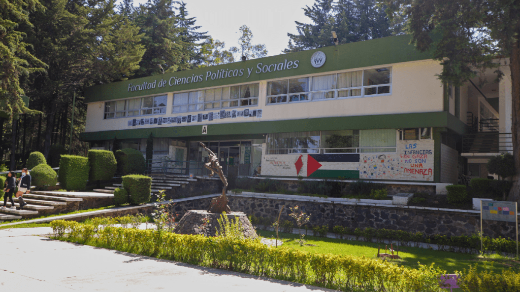 Facade of the Faculty of Political and Social Sciences building with greenery and sculptures in the foreground.