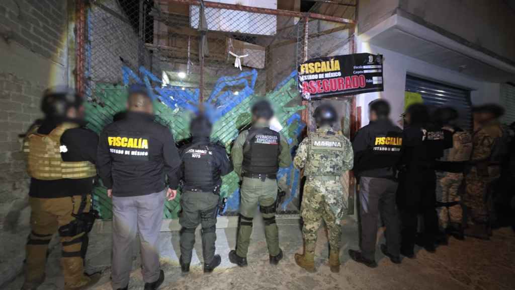 Imagen de un grupo de oficiales de seguridad en la noche, frente a una reja con un cartel que dice 'ASEGURADO'.