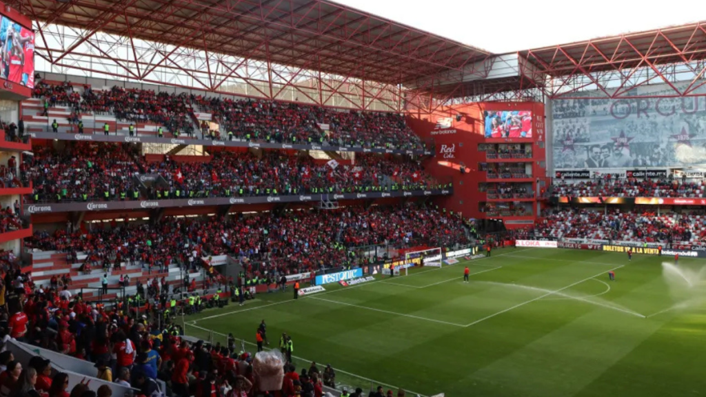 Vista panorámica del estadio Nemesio Diez lleno de espectadores, con una atmósfera vibrante y banners visibles, durante un evento deportivo.