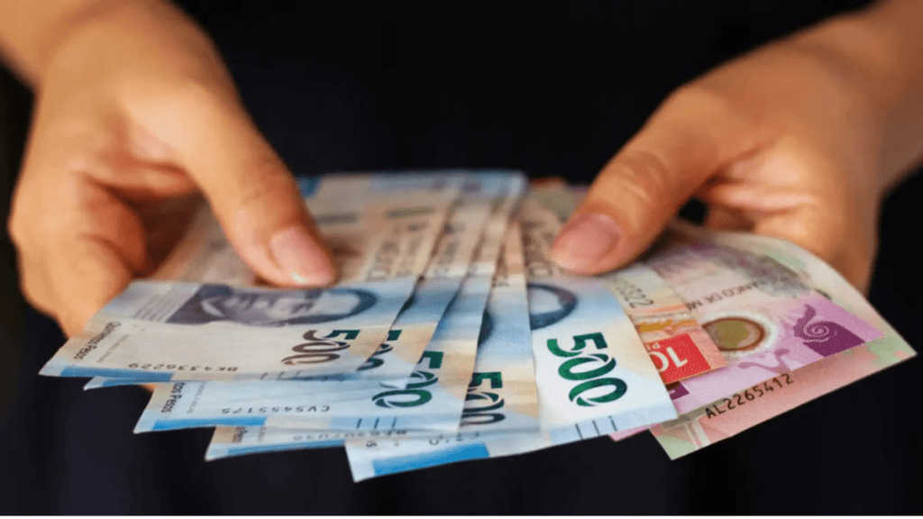 Mano sosteniendo varios billetes de 500 pesos mexicanos.