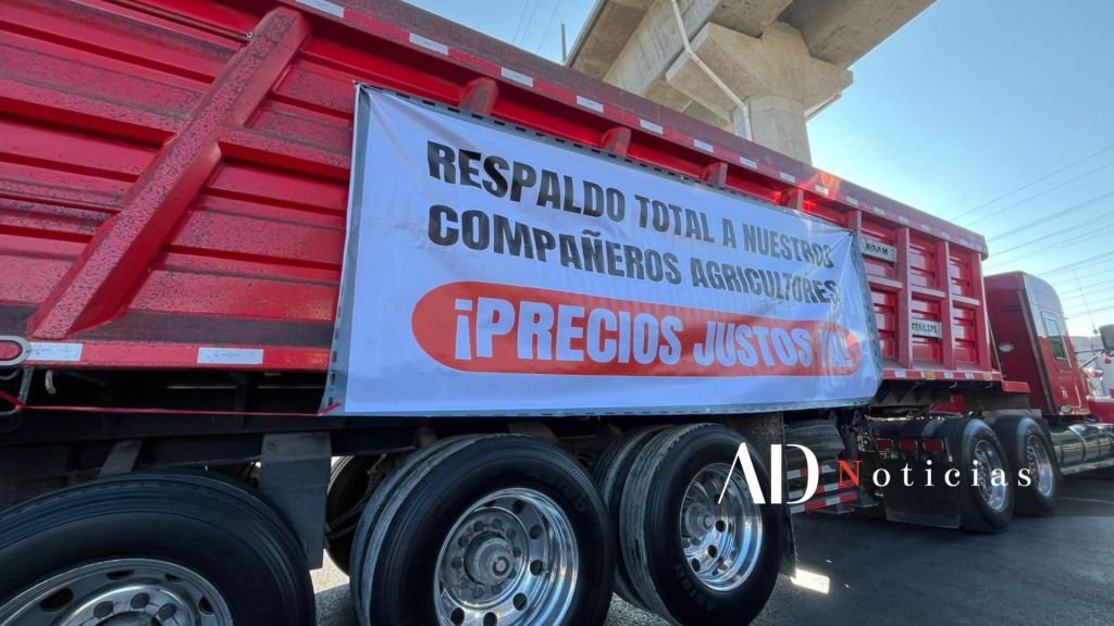 Camión con un cartel que dice 'RESPALDO TOTAL A NUESTROS COMPAÑEROS AGRICULTORES ¡PRECIOS JUSTOS!' estacionado bajo un puente.