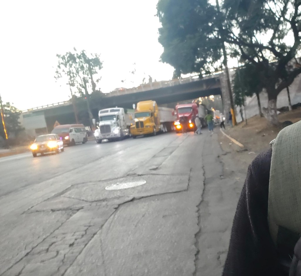 Vista de carreteras parcialmente bloqueadas por camiones en México, con vehículos detenidos y manifestantes en la escena.