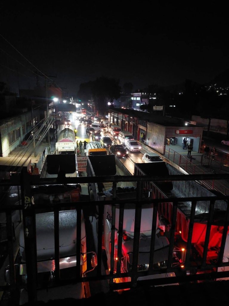 Vista nocturna de un tráfico denso en una carretera en México, con camiones y vehículos atrapados debido a un bloqueo.