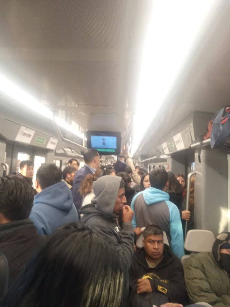 Interior de un vagón de tren interurbano con un gran número de pasajeros, algunos de pie, debido a la alta demanda.