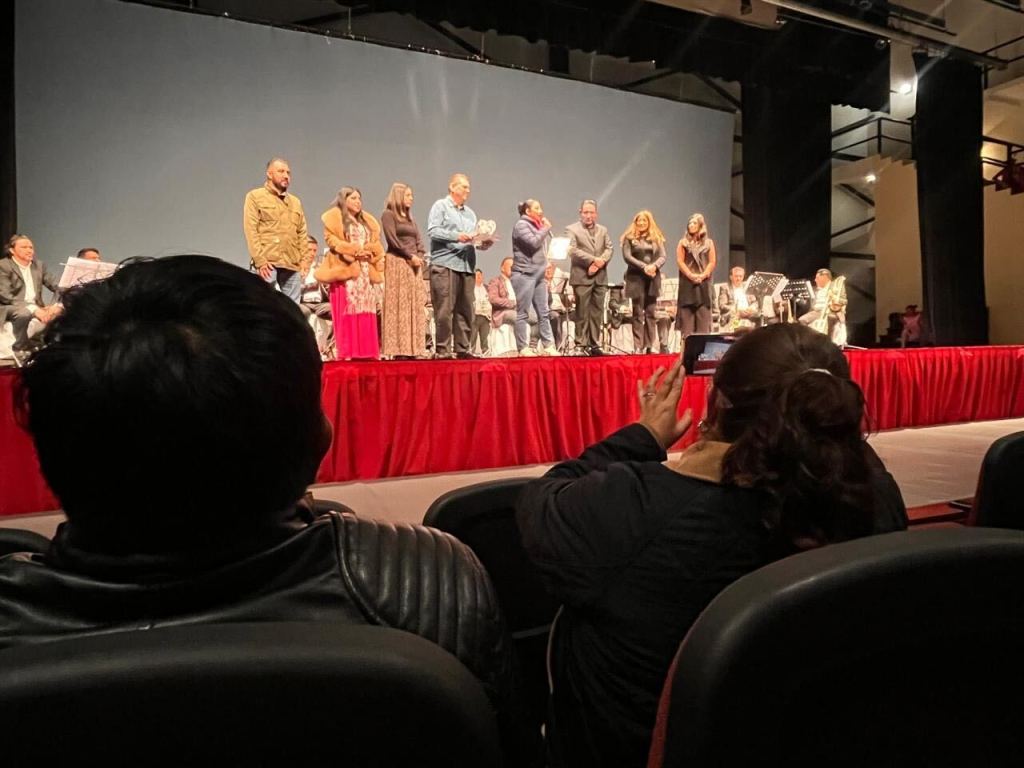 Un grupo de personas en el escenario durante el concierto de aniversario de la Banda Sinfónica Municipal de Lerma, con músicos y asistentes en un ambiente festivo.