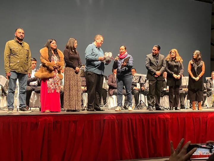 Un grupo de personas en un escenario durante la celebración del 40 aniversario de la Banda Sinfónica Municipal de Lerma, mientras se lleva a cabo una entrega de reconocimientos.