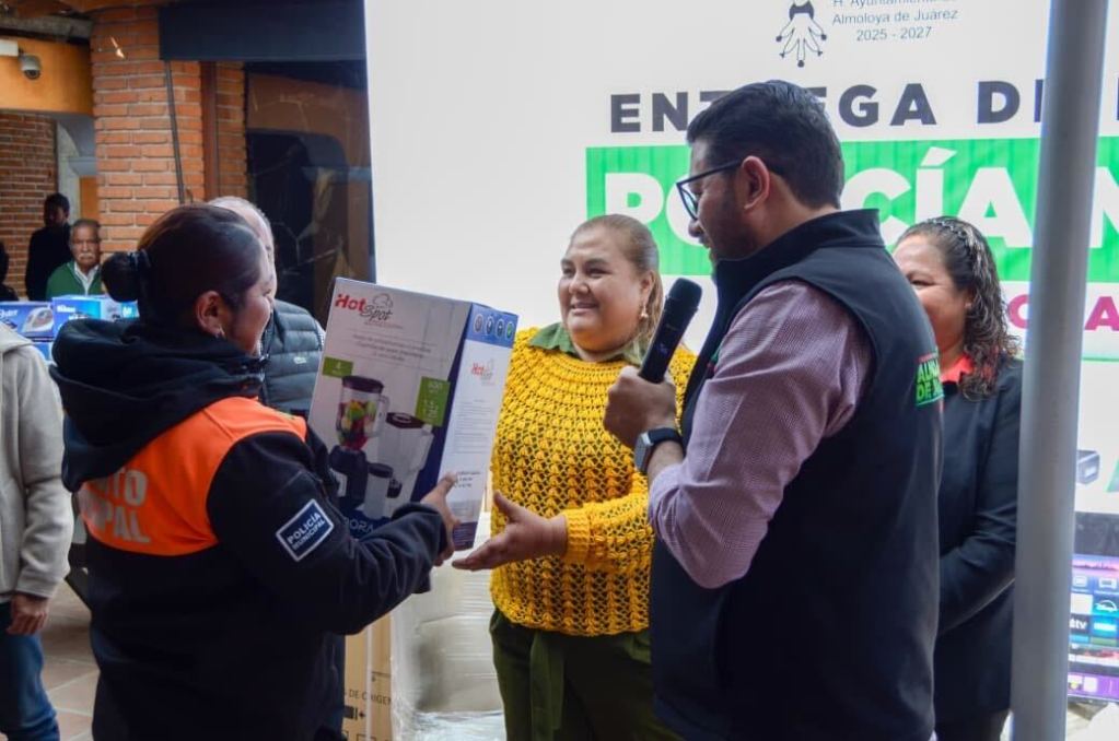 Entrega de equipamiento a la Policía Municipal de Almoloya de Juárez, con un funcionario hablando y entregando un paquete a una oficial.