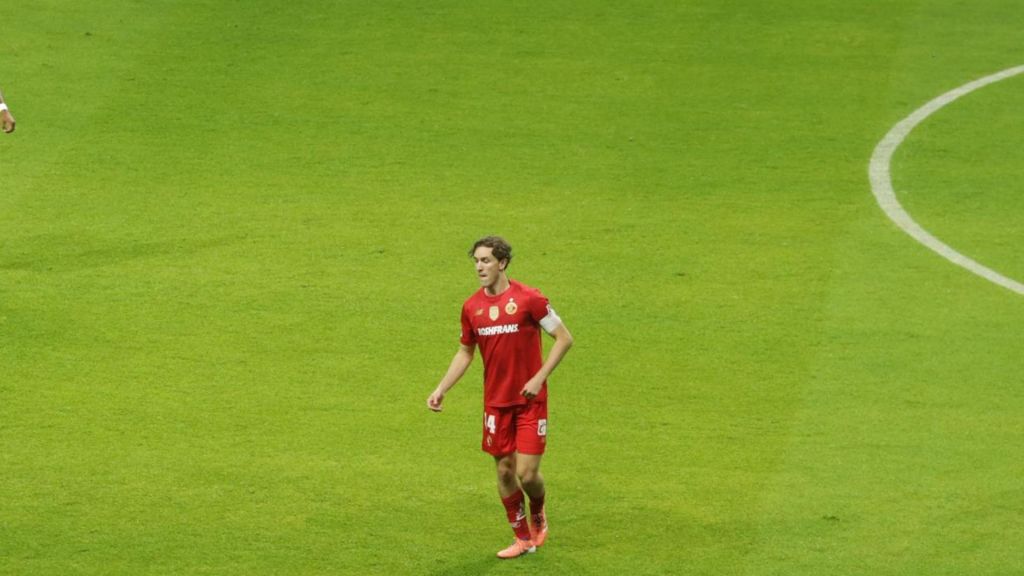 Jugando en el campo, un jugador del equipo de fútbol de Toluca con camiseta roja y el número 14, camina en el césped durante un partido.