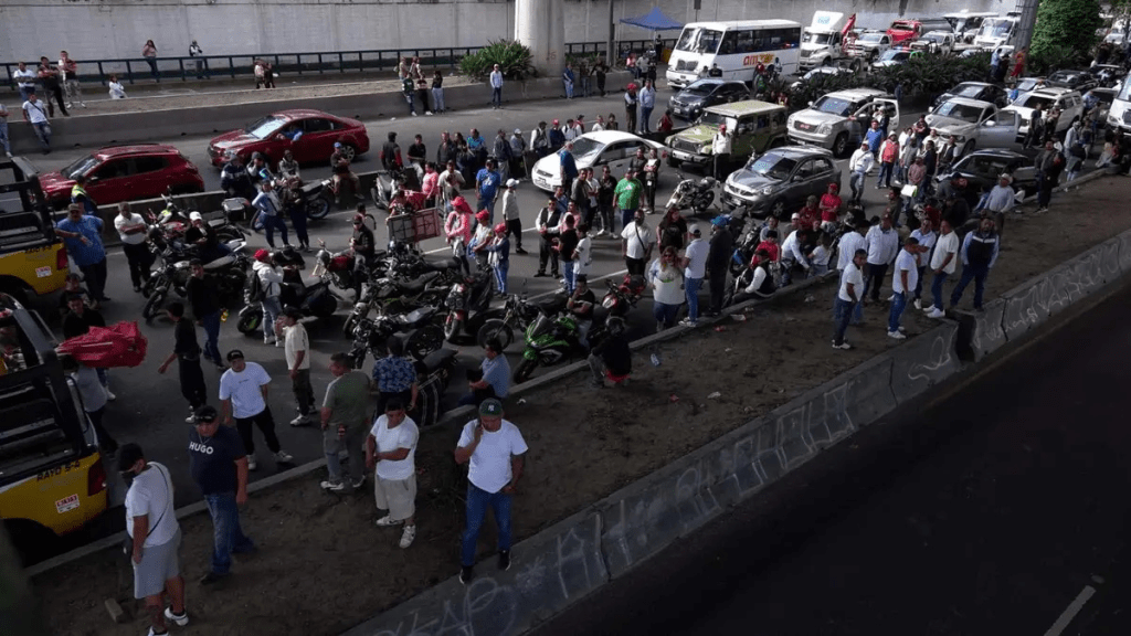 Multitud de manifestantes bloquean una carretera con vehículos en un megabloqueo nacional en México, causando congestión vehicular.