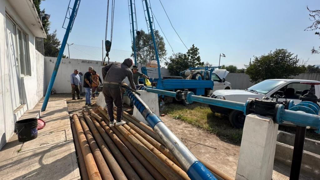 Trabajadores de mantenimiento hidráulico instalando una bomba de agua en la colonia Luis Echeverría, Cuautitlán Izcalli, rodeados de tuberías y equipos en un entorno al aire libre.