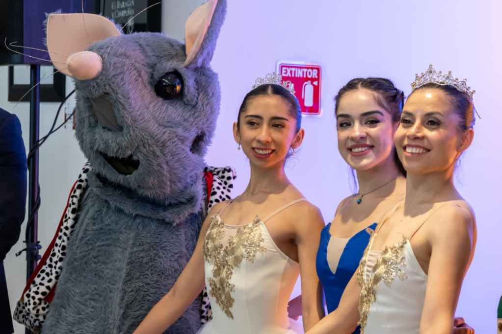 Tres bailarinas en trajes de ballet posan junto a un personaje de disfraz de rey ratón en un evento de promoción del espectáculo 'El Cascanueces'.