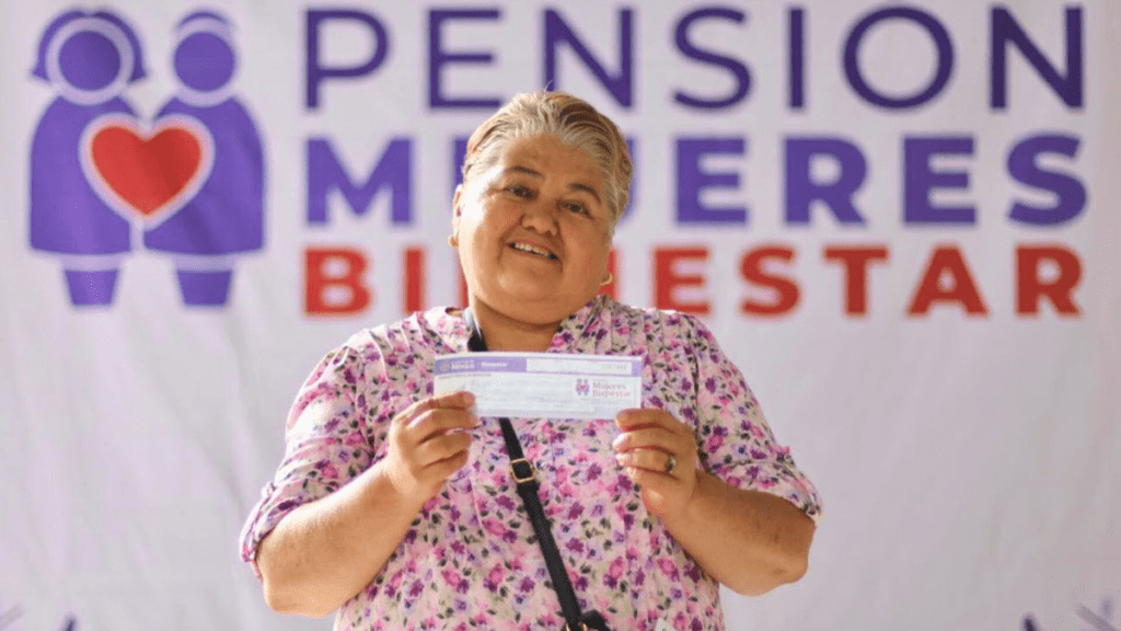 Mujer sonriente sosteniendo un cheque frente a un fondo con el texto 'PENSIÓN MUJERES BIENESTAR'.