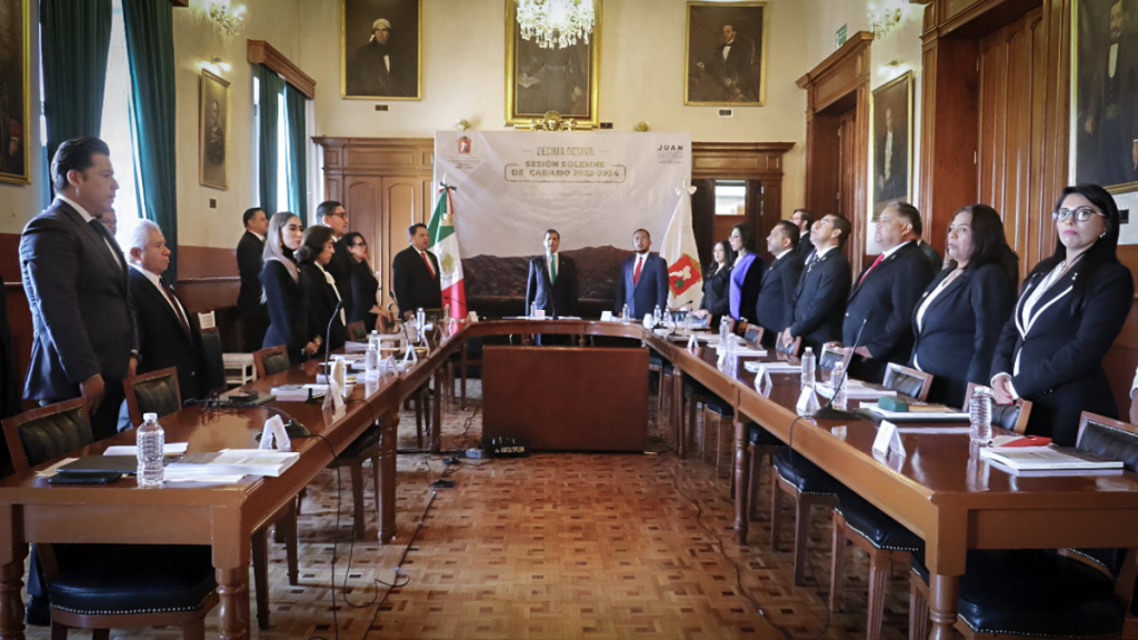 Reunión formal de funcionarios del Órgano Superior de Fiscalización del Estado de México en una sala con decoraciones clásicas, con banderas y retratos en las paredes.
