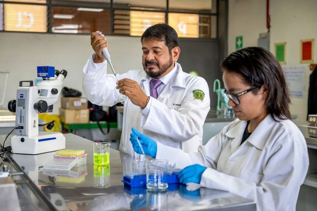 Un profesor y una estudiante trabajan juntos en un laboratorio, utilizando pipetas y frascos, en un ambiente de investigación científica.