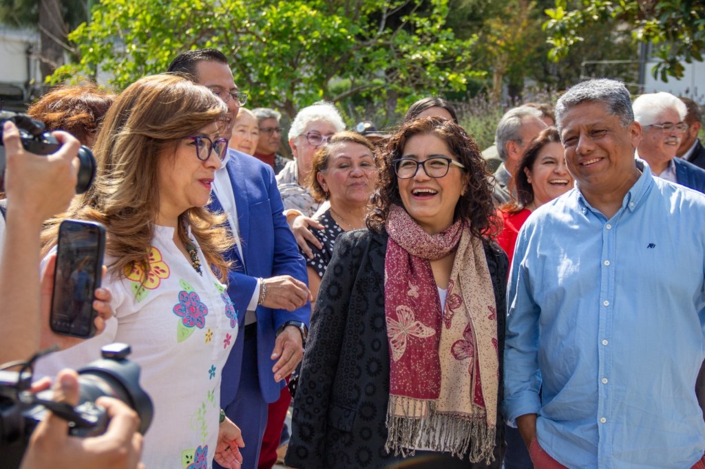 La rectora de la UAEMéx, Martha Patricia Zarza Delgado, y otros miembros de la comunidad educativa participan en el inicio del mural 'El Nigromante, legado y huella de un visionario', sonriendo y conversando entre ellos.