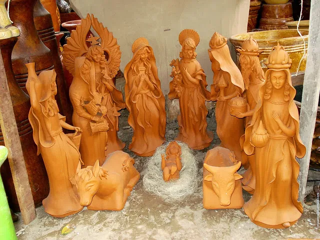 Conjunto de figuras de barro para nacimiento navideño, incluyendo personajes tradicionales como la Virgen María, San José, y el Niño Jesús, rodeados de elementos decorativos.