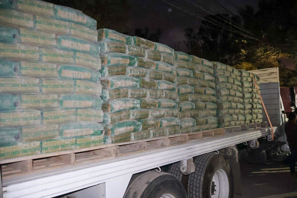 Camión cargado con sacos de cemento, mostrando una pila organizada de materiales de construcción listos para ser entregados a las comunidades.