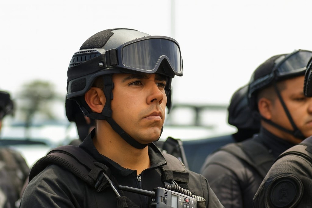 Un grupo de policías en uniforme, uno de ellos en primer plano con mirada seria, en un ambiente de seguridad pública.