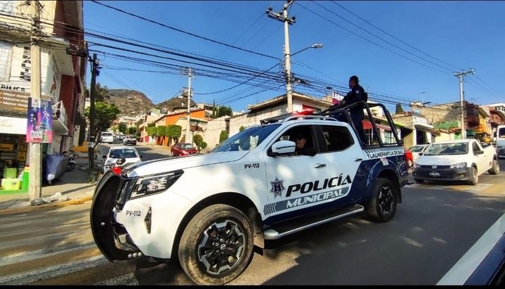 Vehículo policial de Tlalnepantla transitando por una calle, con policías en la parte superior.