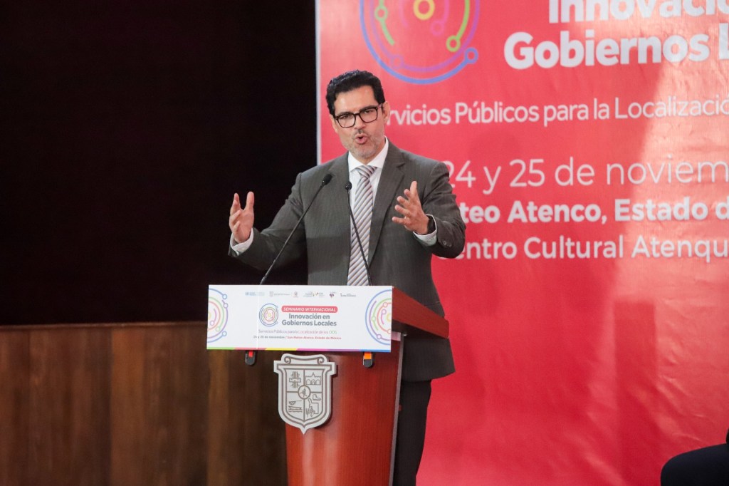 Un orador presenta un discurso durante el Seminario Internacional de Gobiernos Locales en San Mateo Atenco, destacando la importancia de la innovación en servicios públicos.