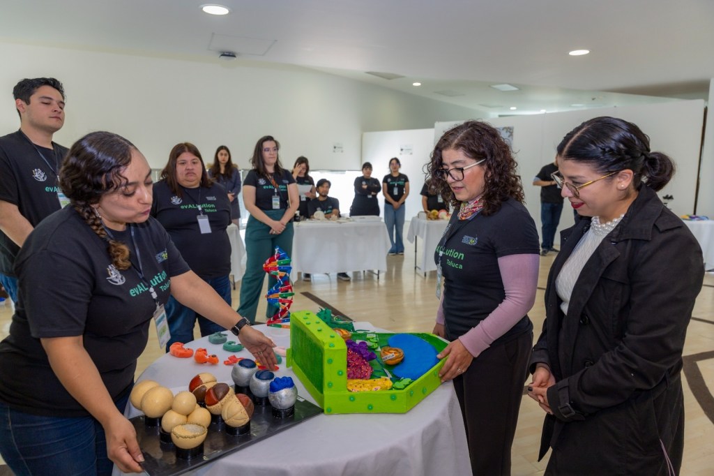 Un grupo de personas participa en una experiencia sensorial inmersiva sobre la evolución y biodiversidad, observando y manipulando modelos educativos.