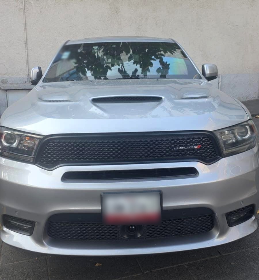 Frente de una camioneta Dodge Durango blanca, con un diseño deportivo en la parrilla y un fondo neutro.