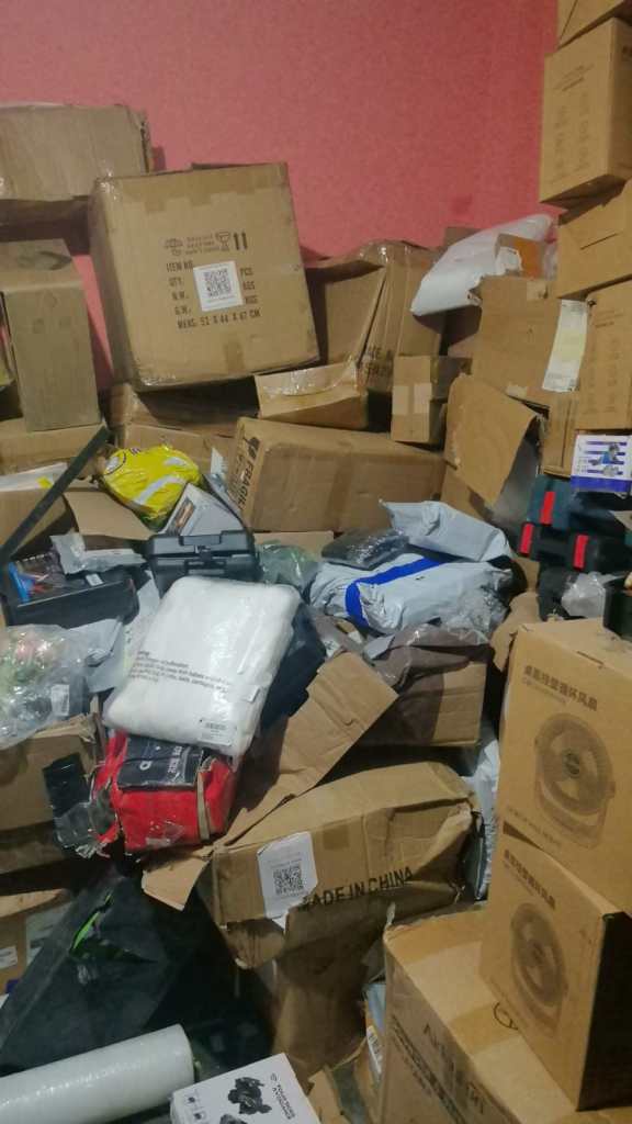 Montones de cajas apiladas en un espacio cerrado, algunas con etiquetas en chino, evidenciando un posible almacenamiento de mercancía ilegal.