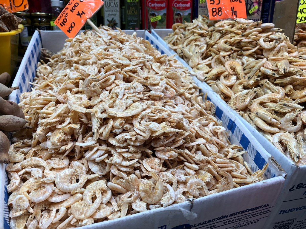 Muestra de camarones secos en el Mercado 16 de Septiembre, apilados en cajas con precios visibles, ideales para la preparación de platillos navideños.
