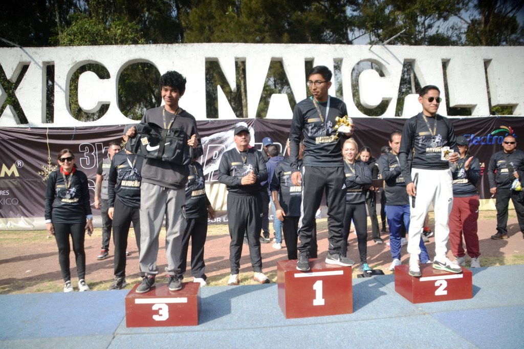 Tres ganadores en el podio de la Primera Carrera Atlética “Navideña” 2025 en Naucalli, sosteniendo sus premios en un ambiente festivo.