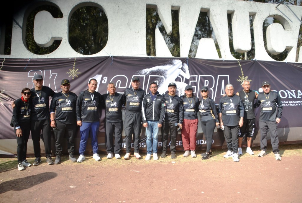 Grupo de participantes en la Primera Carrera Atlética 'Navideña' 2025 de CUSAEM, posando frente a una pancarta del evento en el Parque Naucalli.