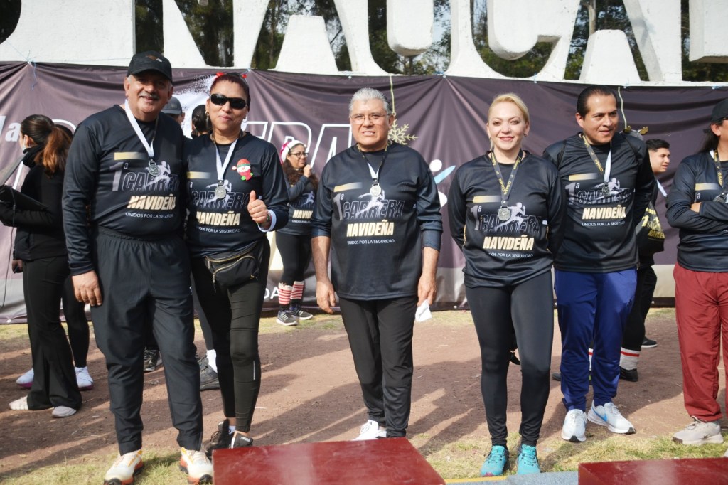 Participantes posando en la Primera Carrera Atlética Navideña 2025, en el Parque Naucalli, Naucalpan, con camisetas y medallas al cuello.