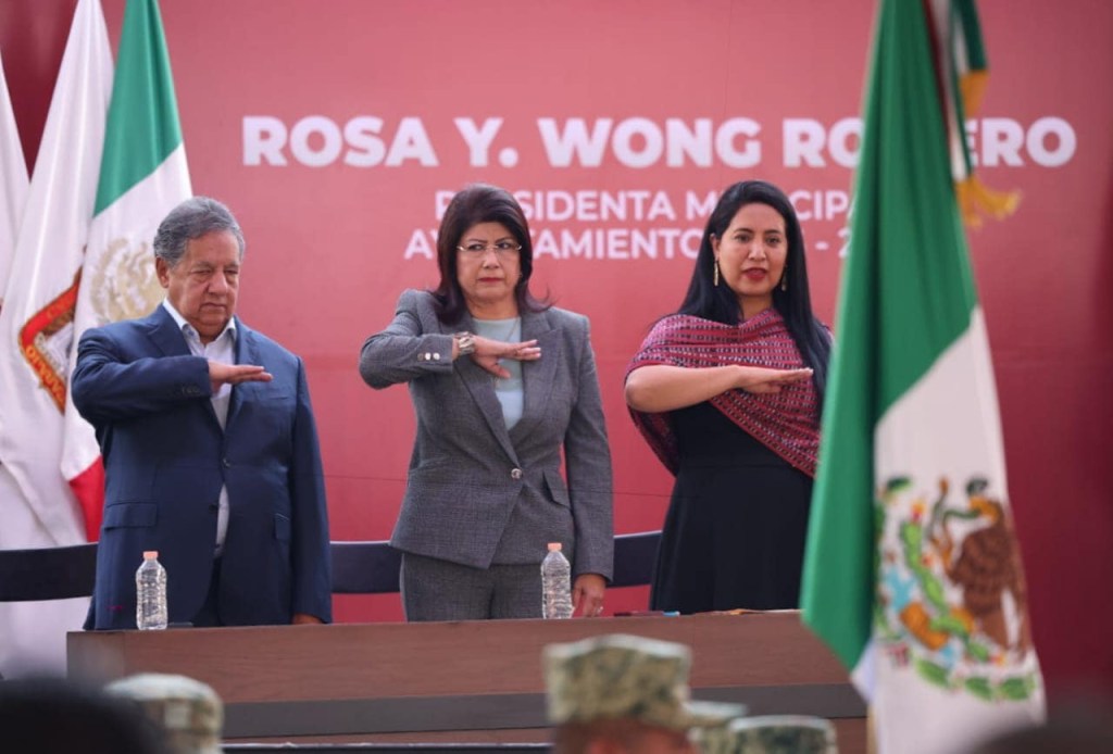 Ceremonia de toma de protesta con la alcaldesa Rosa Wong y otros funcionarios, con banderas de México y del Estado de México de fondo.