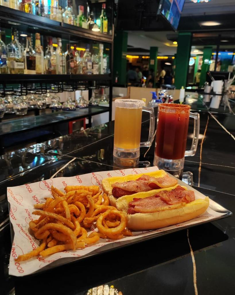 Plato con papas fritas en espiral, salchichas y cervezas en un bar