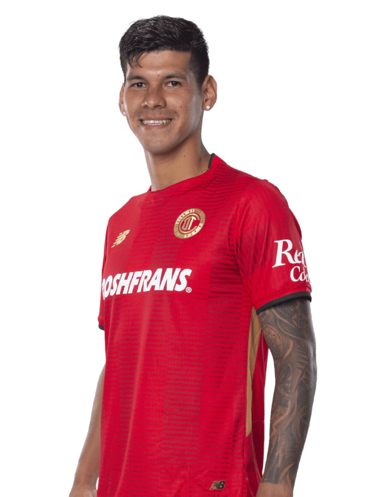 Jugador de fútbol posando con una camiseta roja del club Toluca, sonriendo y mostrando una actitud confiada.