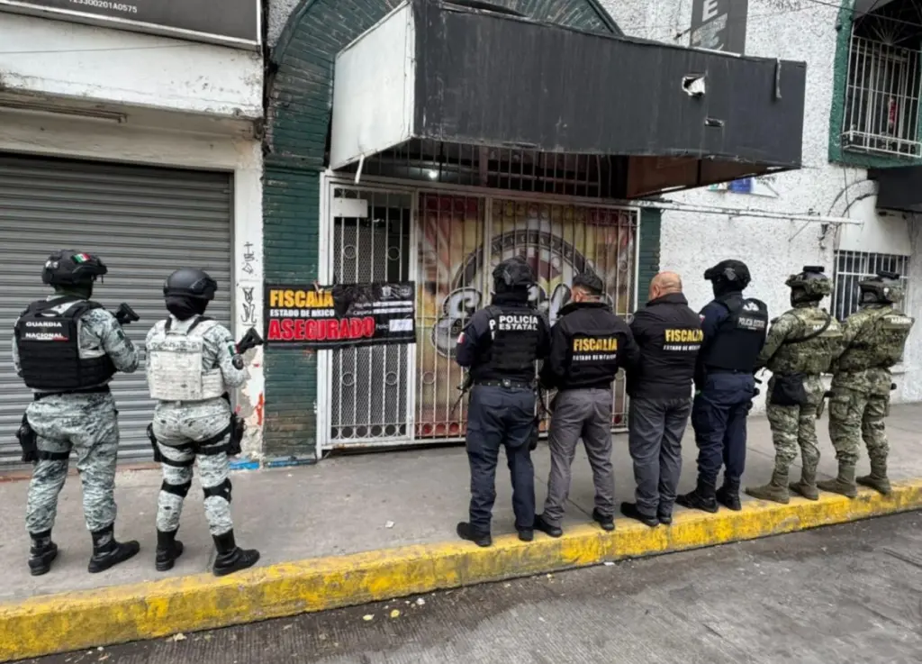 Grupo de oficiales de seguridad, incluyendo policía estatal y fuerzas armadas, frente a un establecimiento asegurado en el Estado de México, con un cartel que indica la intervención de la fiscalía.