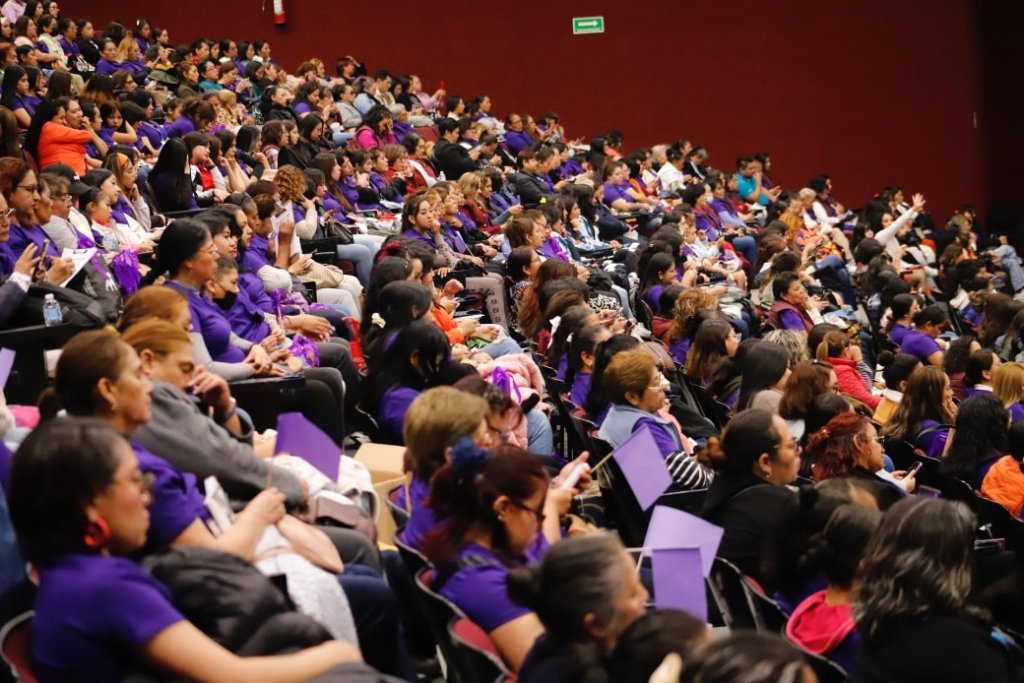 Audiencia masiva de mujeres en un evento enfocado en la participación ciudadana y la prevención del delito, la mayoría de ellas vestidas con camisetas moradas.