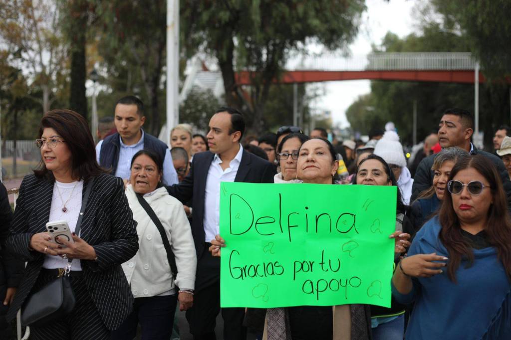 Un grupo de personas marcha en una calle sosteniendo un cartel verde que dice 'Delfina, gracias por tu apoyo'.